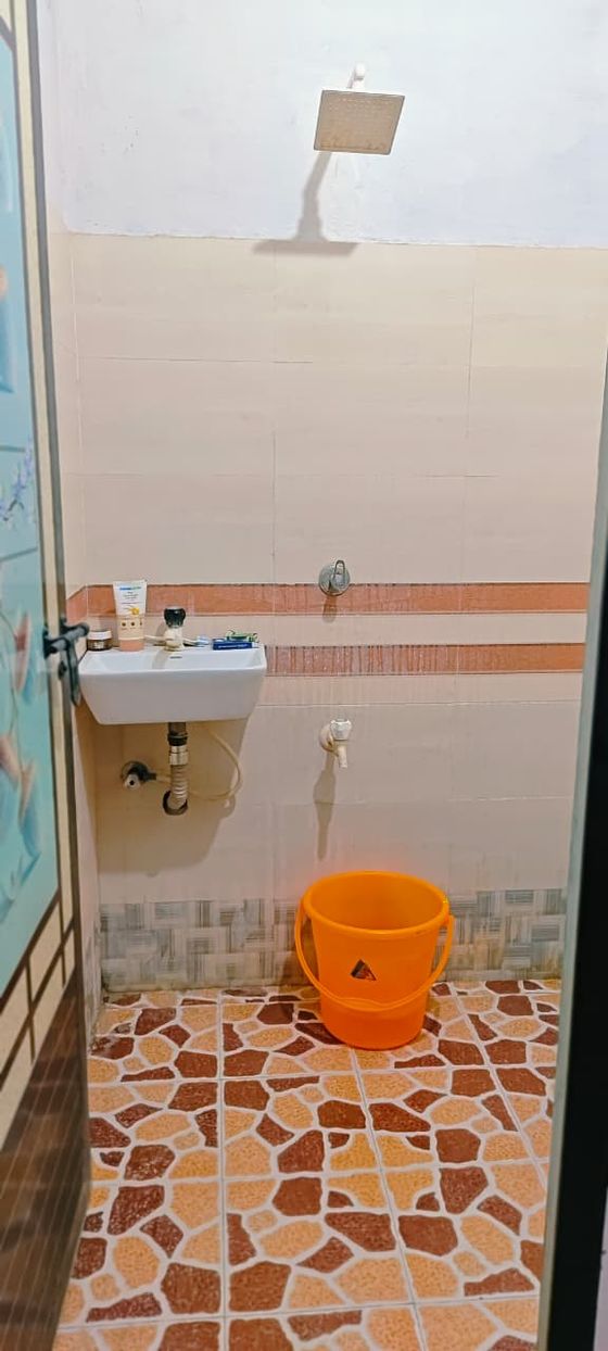 The dormitory bathroom: a washbasin and a bucket on a tiled floor