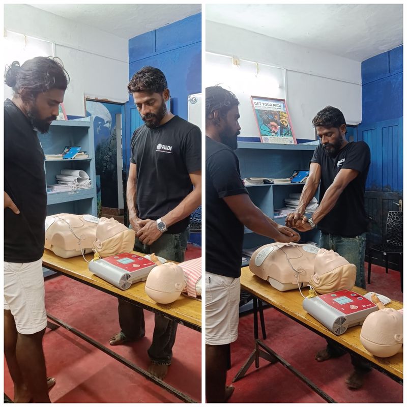 Two Lak Scuba staff in the dive centre classroom with adult and infant CPR manikins and an AED trainer, one practising chest compressions