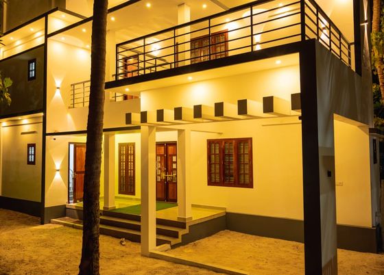 A two-storey partner guest house lit up at night, with steps up to the entrance and sand in front